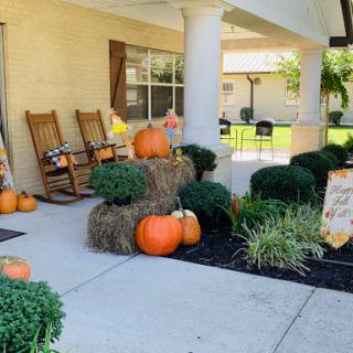 A cozy autumn-themed front porch adorned with pumpkins and hay bales.