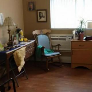 A cozy room with a rocking chair, dresser, and window letting in natural light.