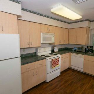 A clean and organized kitchen featuring wooden cabinets, a stove, microwave, refrigerator, and dishwasher.