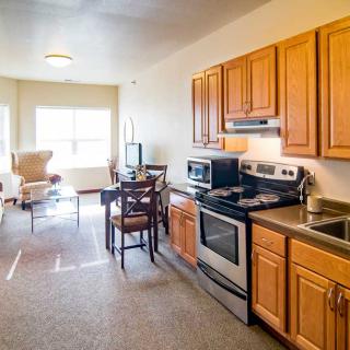 A modern open-plan kitchen and living area with wooden cabinets and stainless steel appliances.