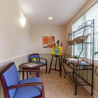 A cozy waiting room with two chairs, a table with a plant, and artwork on the wall.