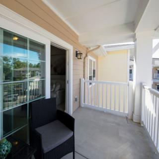 A sunny balcony with a chair and white railings.