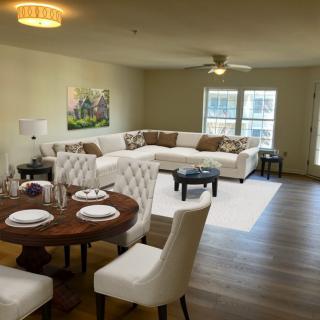 A modern living room with a dining area featuring a white sectional sofa and a round dining table set on wood flooring.
