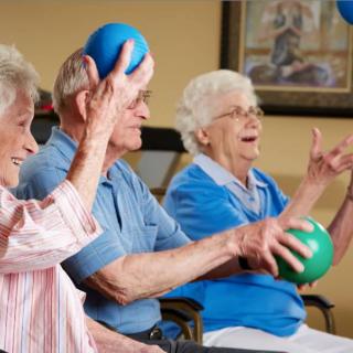 A group of elderly people participating in a fun exercise activity with colorful balls.
