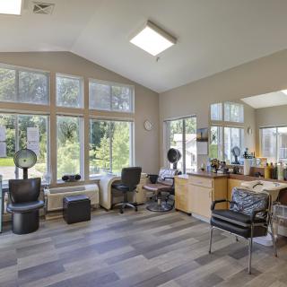 A modern hair salon interior with large windows and daylight streaming in.