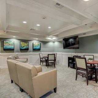 A modern lounge area featuring comfortable seating, tables and chairs, wall art, and a mounted TV.