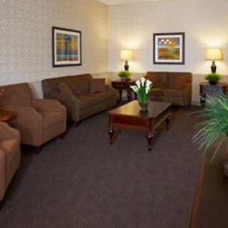 A cozy living room with brown sofas and armchairs surrounding a wooden coffee table, complemented by lamps and decorative artwork.