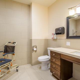 An accessible bathroom featuring a wheelchair, sink, and toilet.