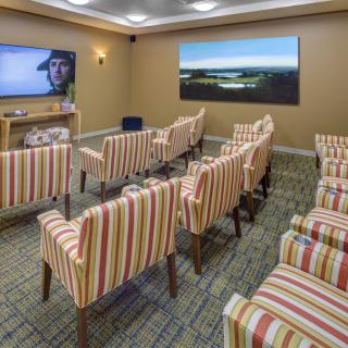 A cozy home theater room with striped chairs arranged in rows facing a large television screen.