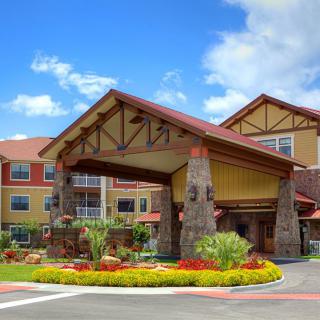 A welcoming hotel entrance with landscaped gardens and a clear blue sky.