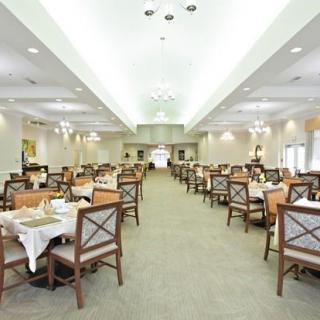 An empty dining hall with neatly arranged tables and chairs under bright lighting.