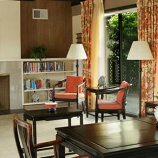 A cozy living room with comfortable seating, a bookshelf, and natural light streaming through the window.