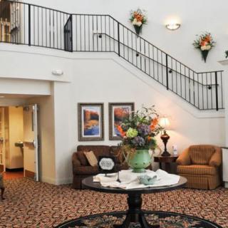 A welcoming lobby with elegant decor, featuring a staircase, sofas, and a floral centerpiece.