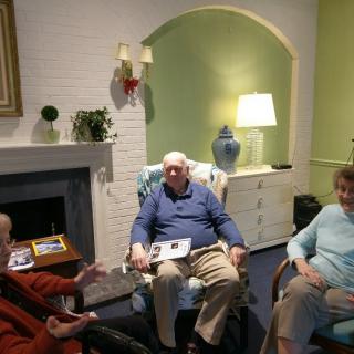 A group of elderly people sitting and conversing in a cozy living room.