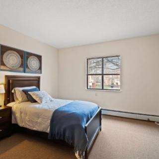 A cozy bedroom with a single bed and wall art, featuring a window allowing natural light to flood in.