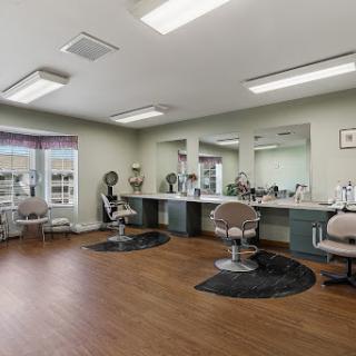 A modern salon interior featuring stylist chairs, mirrors, and a warm wooden floor.