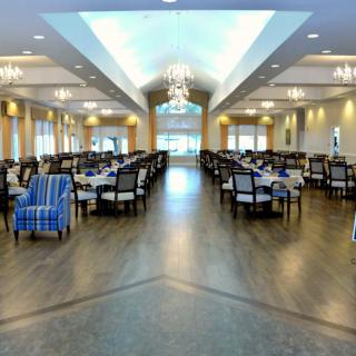 An elegant dining room with tables and chairs arranged symmetrically under chandeliers.