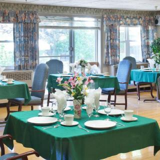 A well-arranged dining room with green tablecloths and floral centerpieces.