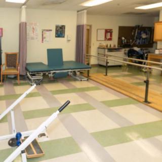 A spacious physical therapy room equipped with parallel bars and exercise equipment, designed for rehabilitation exercises.