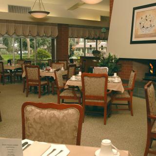 An elegant dining room with neatly arranged tables and chairs, featuring large windows and tasteful decor.