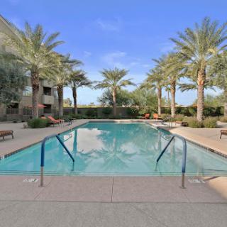 A serene swimming pool surrounded by palm trees at an apartment complex, perfect for relaxation.