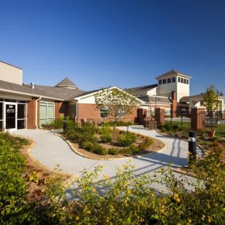 A modern building surrounded by landscaped gardens and pathways on a clear day.