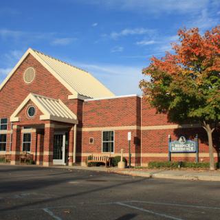 A brick building set against a blue sky with autumn foliage.