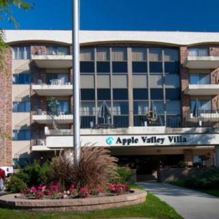 The exterior of Apple Valley Villa, a residential apartment building with balconies and landscaped surroundings.