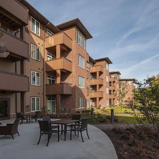 A modern apartment building with outdoor seating and landscaped surroundings.