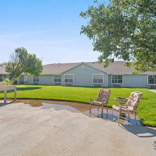 A spacious backyard with a neatly maintained lawn and a seating area on the patio.