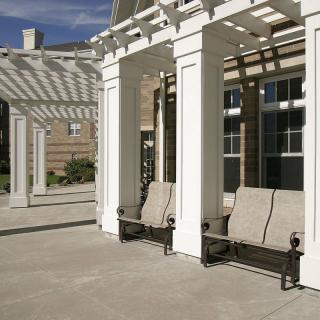An outdoor area featuring a white pergola with benches underneath, providing a shaded seating space.