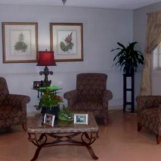 A cozy living room with patterned chairs, a central table, a lamp, and decorative artwork on the wall.
