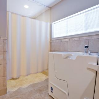 An accessible bathroom featuring a walk-in tub and a shower with tiled walls.