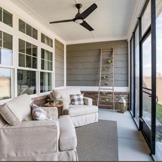 A cozy screened porch with comfortable seating and a ceiling fan.