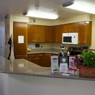 A view of a modern kitchen featuring wooden cabinets, a countertop, and essential appliances.