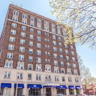 A brick hotel building with blue awnings under a clear sky.