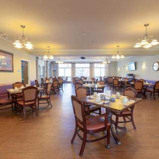 An empty dining room with neatly arranged tables and chairs, illuminated by warm lighting.