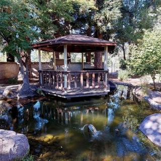 A tranquil gazebo overlooking a serene pond surrounded by lush trees.