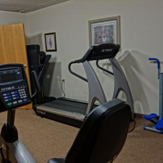 A small gym setup with various exercise equipment including a treadmill and stationary bike.