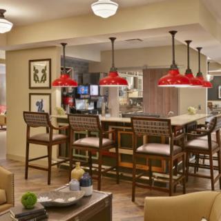 A modern kitchen with a bar area featuring red pendant lights and comfortable seating.