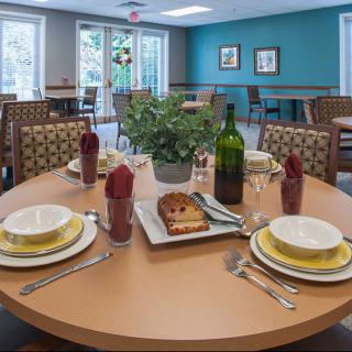 A neatly set dining table with plates, cutlery, and a wine bottle in a cozy dining room.