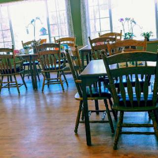 An empty cafe with wooden chairs and tables, featuring a bright and inviting atmosphere.