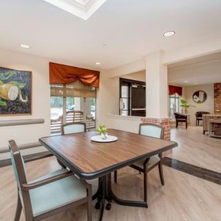 A modern dining area with a polished table, comfortable chairs, and decorative artwork on the walls.