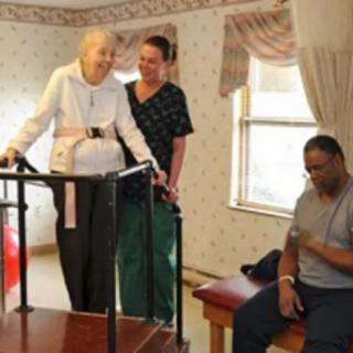 An elderly woman receiving assistance during a physical therapy session.