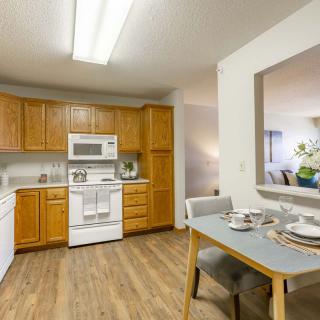 A cozy kitchen and dining area featuring wooden cabinets, white appliances, and a neatly set dining table.