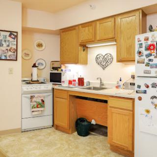 A cozy kitchen featuring wooden cabinets, essential appliances, and a warm atmosphere.