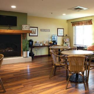 A cozy living room with a fireplace, tables and chairs on a wooden floor.
