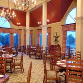 A spacious restaurant dining room with elegant chandeliers and neatly arranged tables and chairs.