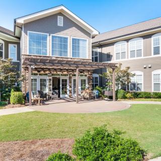 A modern residential building with a landscaped garden and patio area.