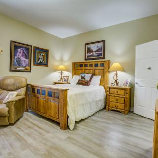 A cozy bedroom featuring wooden furniture, decorative wall art, and a comfortable armchair.